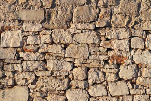Ancient medieval stone masonry. Texture of a fragment of a wall of an old structure. A background for design and creative work. Decoration and exterior decoration of the building. Construction works.