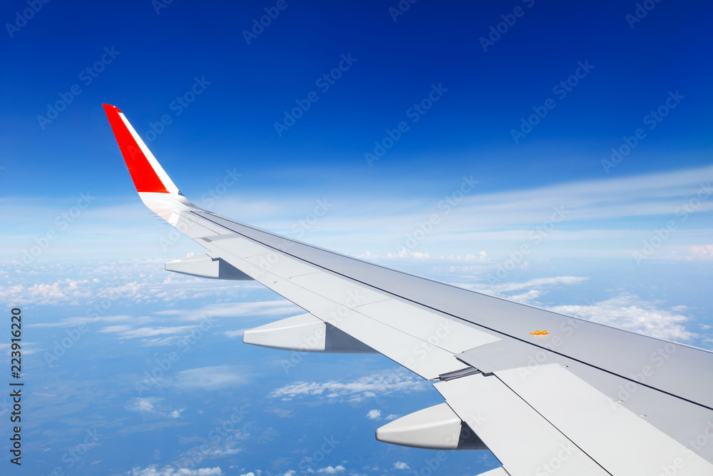 Wing of the aircraft on the background of clouds and bright blue sky Wing of the aircraft on the background of clouds and bright blue sky