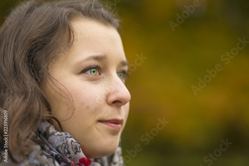 Close up Portrait of beautiful young smile woman in fall beech forest with yellow leaves around. Detail view on girl beauty with empty space in easy colorful background of tree crown.
