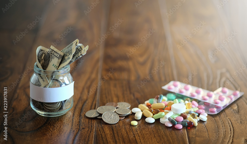 Drugs and coins in a glass jar on a wooden floor. Pocket savings Drugs and coins in a glass jar on a wooden floor. Pocket savings