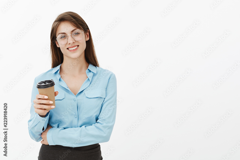 Day cannot start with nice cup of coffee. Joyful attractive female entrepreneur in glasses and blue blouse, holding hand crossed on chest and drinking beverege, smiling broadly, enjoying lunch break Day cannot start with nice cup of coffee. Joyful attractive female entrepreneur in glasses and blue blouse, holding hand crossed on chest and drinking beverege, smiling broadly, enjoying lunch break