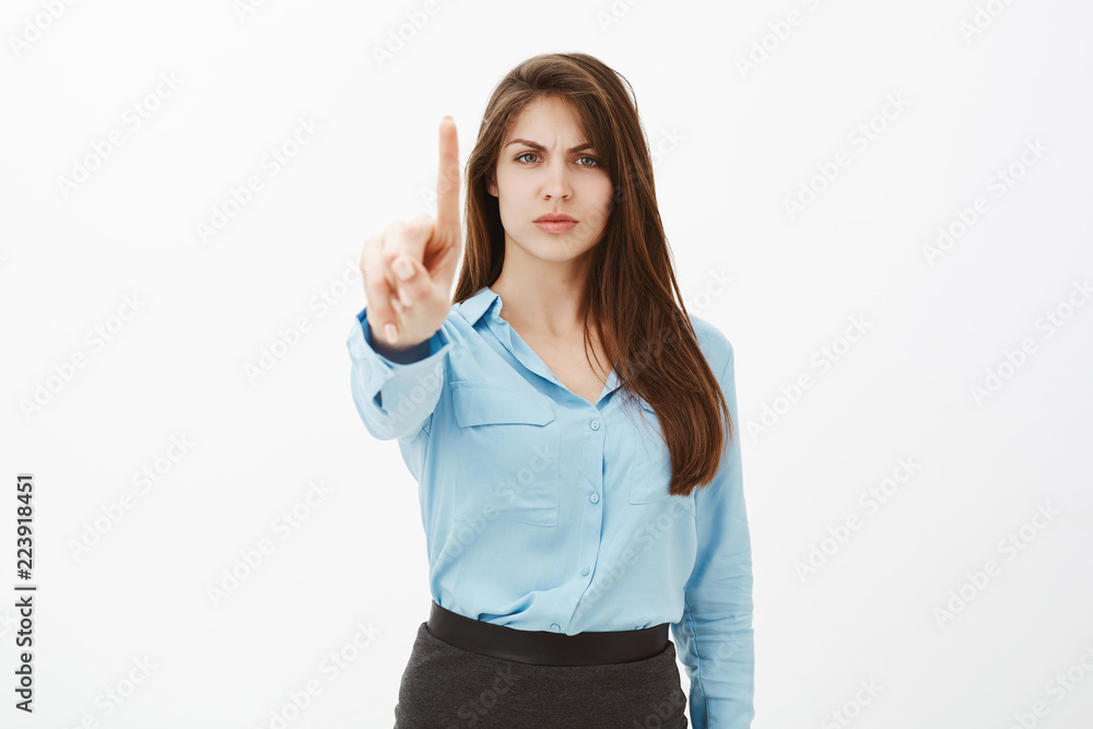 Hold on, wait a sec. Bossy displeased attractive entrepreneur in blue official blouse, frowning and pulling index finger towards camera in disapproval gesture, scolding or giving instructions Hold on, wait a sec. Bossy displeased attractive entrepreneur in blue official blouse, frowning and pulling index finger towards camera in disapproval gesture, scolding or giving instructions