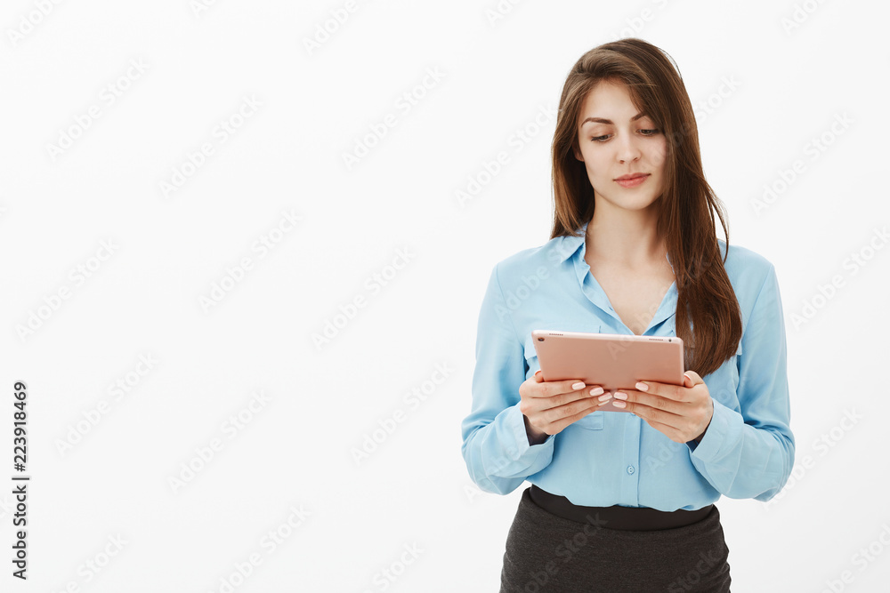 Girl checking schedule in digital tablet, making plans for day. Happy carefree european female in blue blouse, holding pink gadget and reading article in internet or messaging in social networks Girl checking schedule in digital tablet, making plans for day. Happy carefree european female in blue blouse, holding pink gadget and reading article in internet or messaging in social networks