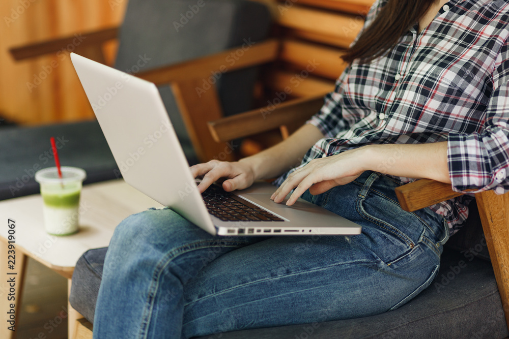 Close up cropped woman in outdoors street wooden cafe sitting in casual clothes, working on modern laptop pc computer, relaxing during free time. Mobile Office. Lifestyle freelance business concept.
