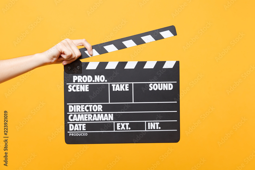 Close up female holding in hand classic director clear empty black film making clapperboard isolated on trending yellow orange background. Cinematography production concept. Copy space for advertising