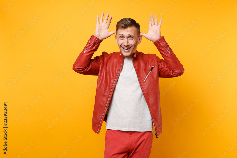 Portrait vogue smiling handsome young man 25-30 years in red leather jacket, t-shirt standing isolated on bright trending yellow background. People sincere emotions lifestyle concept. Advertising area Portrait vogue smiling handsome young man 25-30 years in red leather jacket, t-shirt standing isolated on bright trending yellow background. People sincere emotions lifestyle concept. Advertising area