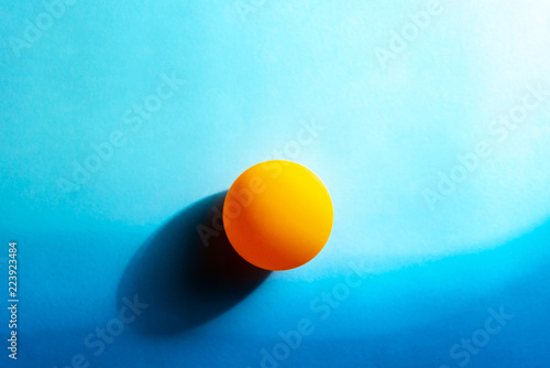 Minimalist sunset by the sea abstract. Ping pong ball on blue background paper.