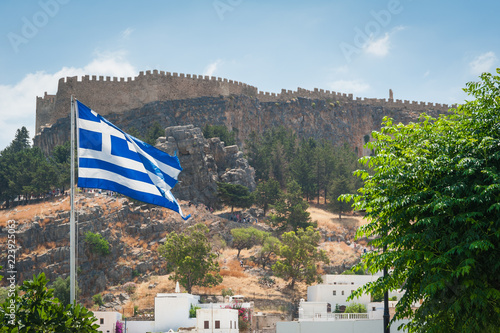 Distant view at Lindos Town and Castle with ancient ruins of the Acropolis on sunny warm day. Island of Rhodes, Greece.