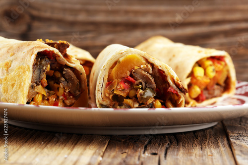 Burritos wraps with beef and vegetables on wooden background. Beef burrito, mexican food