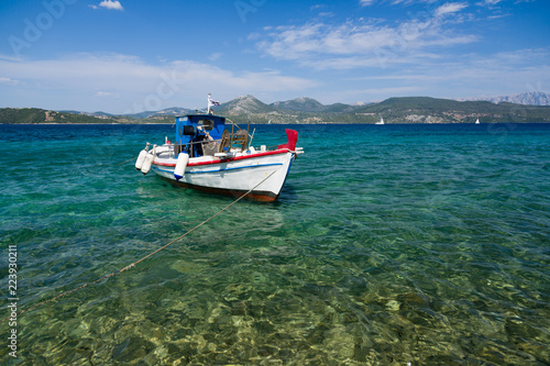 White fisher boat floats on crystal clear water in Greece