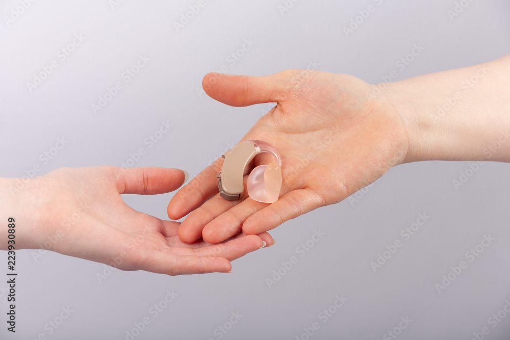 Hands holding a hearing aid