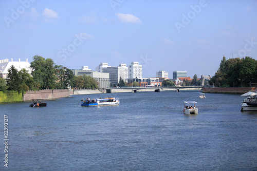 Statki i łodzie na rzece Odrze we Wrocławiu, nabrzeże, most i biurowce.