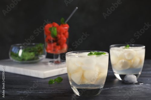 Glasses with tasty melon ball drinks on dark table