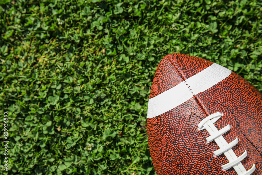 Obraz premium Ball for American football on fresh green field grass, top view. Space for text