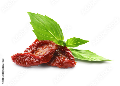 Tasty sun dried tomatoes with green leaves on white background photo