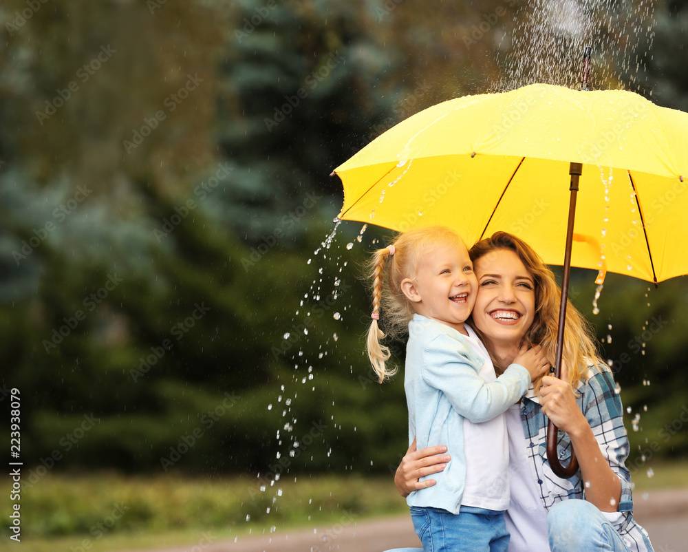 Happy mother and daughter with umbrella under rain in park. Space for text - obrazy, fototapety, plakaty 