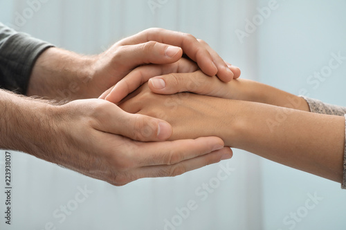 Man holding woman's hands against blurred background, closeup. Concept of support and help