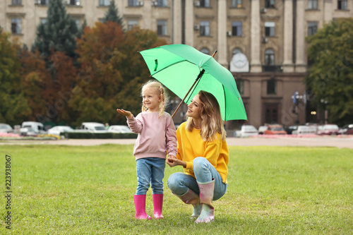 Happy mother and daughter with umbrella in park © New Africa