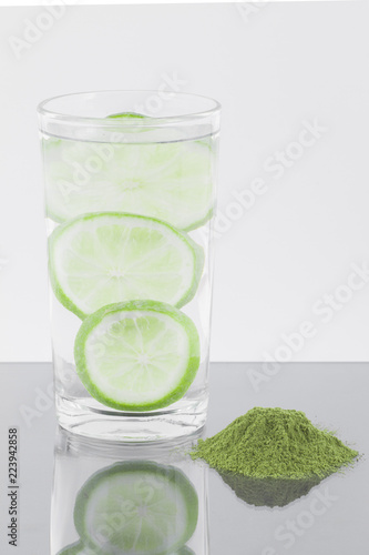 Moringa powder with lemon and glass with water isolated on white background