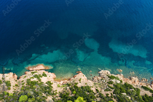 Spectacular aerial view of a beautiful wild and rocky coast bathed by a clear and turquoise sea, Sardinia, Italy.