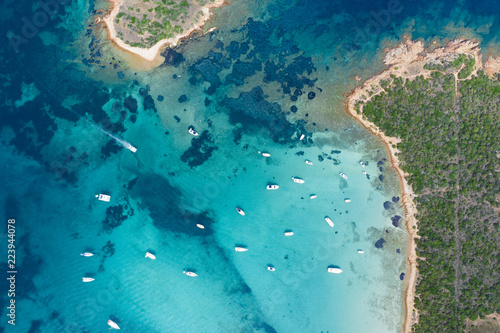 Fototapeta Naklejka Na Ścianę i Meble -  Spectacular aerial view of some yachts and small boats floating on a clear and turquoise sea, Sardinia, Italy.