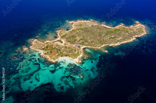 Spectacular aerial view of a little island bathed by a clear and turquoise sea, Sardinia, Italy.