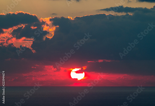 beautiful sunset with red sun on the black sea with clouds photo