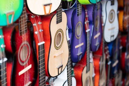 Fototapeta Naklejka Na Ścianę i Meble -  Rows of colorful practice guitars for kids hanging on the wall of a street vendor.