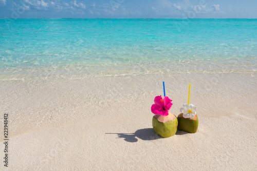 Tropical fresh coconut cocktail on white beach.