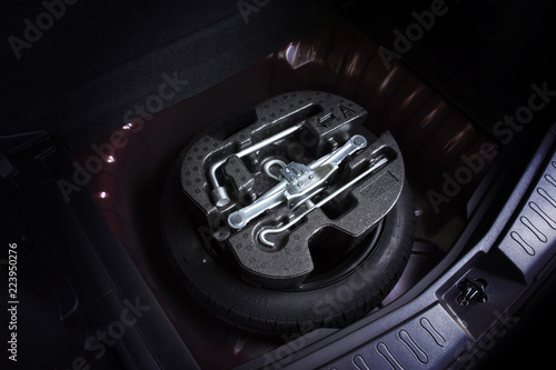 Car jack and wheel changing tool kit in spare tyre of car, automotive part concept.