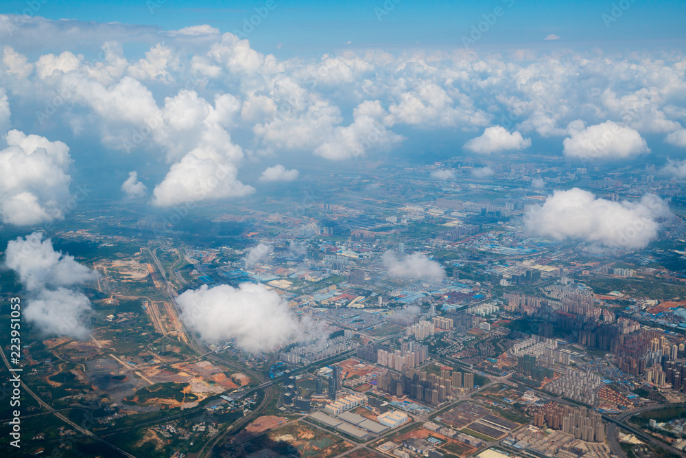aerial view, flying above the puffy white clouds and over ground landscape in China, Asia.