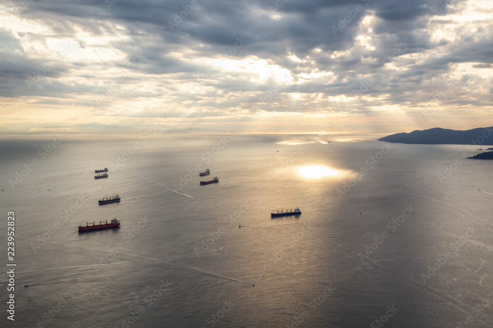 Aerial view of the ships in Burrard Inlet during a vibrant summer sunset. Taken in Vancouver, BC, Canada.