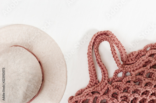 Women's hat with wide flaps and knitted beach bag of pink color. Top view. Copy space.