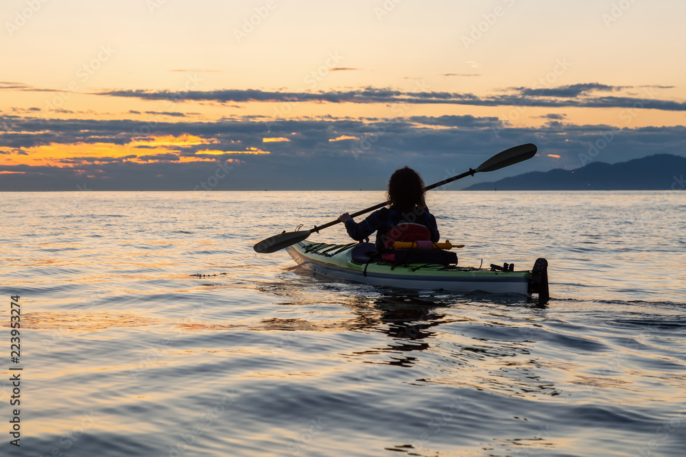 Girl Sea Kayaking during a vibrant sunny summer sunset. Taken in Vancouver, BC, Canada.