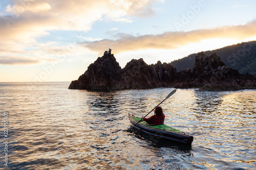 Girl kayaking in the Pacific Ocean during a cloudy summer sunset. Taken in San Josef Bay  Cape Scott  Northern Vancouver Island  BC  Canada.