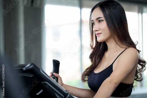 Young sexy fitness woman in sport wear working out on exercise machine in the gym.