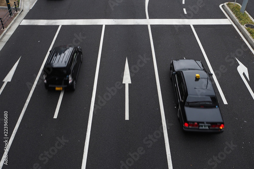 Two cars moving in five paved lanes with direction signs
