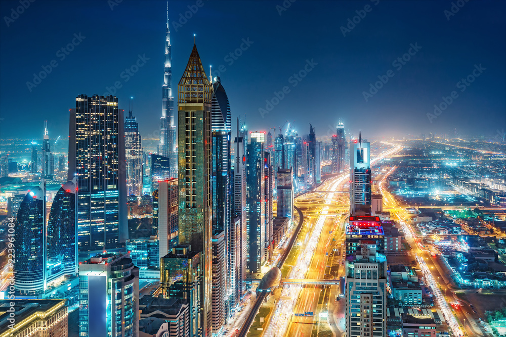 Naklejka premium Spektakularna miejska panorama z kolorowymi iluminacjami miasta. Widok z lotu ptaka na autostrady i drapacze chmur w Dubaju, w Zjednoczonych Emiratach Arabskich.