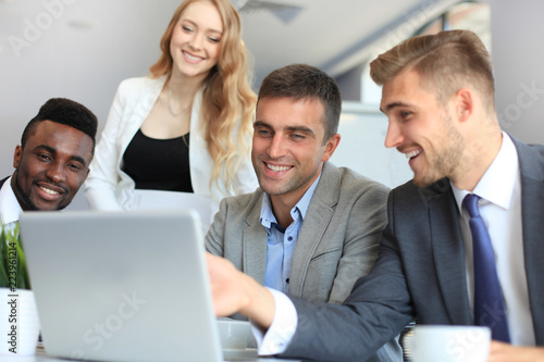 Brainstorm. Group of business people looking at the laptop together. One business woman looking at camera.