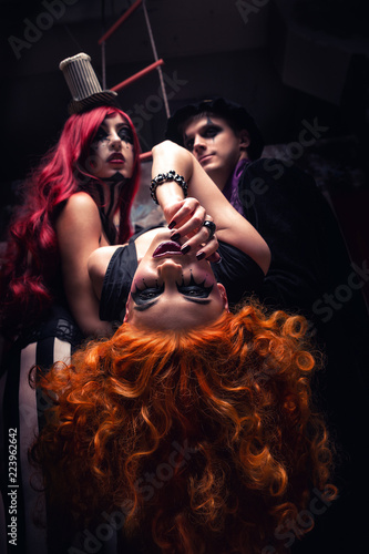 Three people performing on stage freak show on dark circus scene background