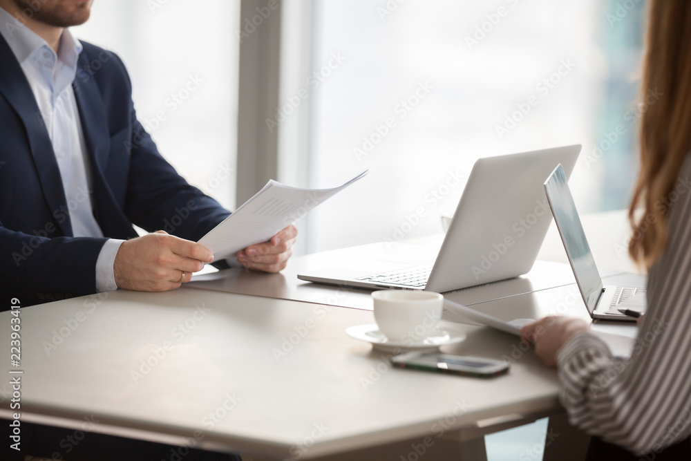 Close up of business partners hold documents or papers considering contract terms, diverse workers or colleagues discuss agreement condition talk or negotiate at meeting in office. Partnership concept Close up of business partners hold documents or papers considering contract terms, diverse workers or colleagues discuss agreement condition talk or negotiate at meeting in office. Partnership concept