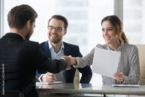 Happy employers shake hand of male job candidate, congratulating with given position, satisfied HR managers happy to hire applicant handshake greeting at team. Successful good interview concept photo