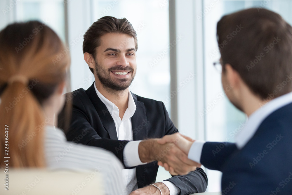 Close up view of HR managers handshake smiling male job candidate congratulating with hiring, happy satisfied employee shake hand employers greeting him, thanking for good interview, welcoming at work Close up view of HR managers handshake smiling male job candidate congratulating with hiring, happy satisfied employee shake hand employers greeting him, thanking for good interview, welcoming at work