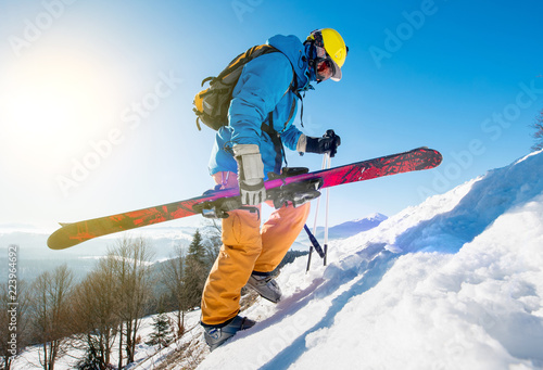 Male skier walking up the snowy hill in the Carpathians mountains carrying his skis copyspace seasonal activity sport sportsman hobby recreation travel concept