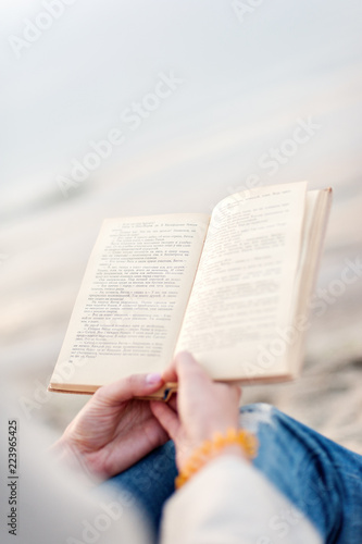 The girl reads the book on sand on the ocean coast