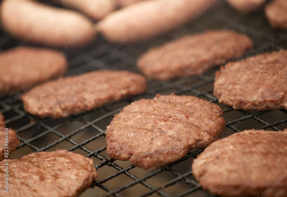 BEEF BURGERS AND SAUSAGES COOKING ON A BARBECUE BEEF BURGERS AND SAUSAGES COOKING ON A BARBECUE