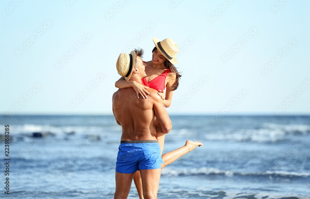 Naklejka premium Happy young couple having fun at beach on sunny day