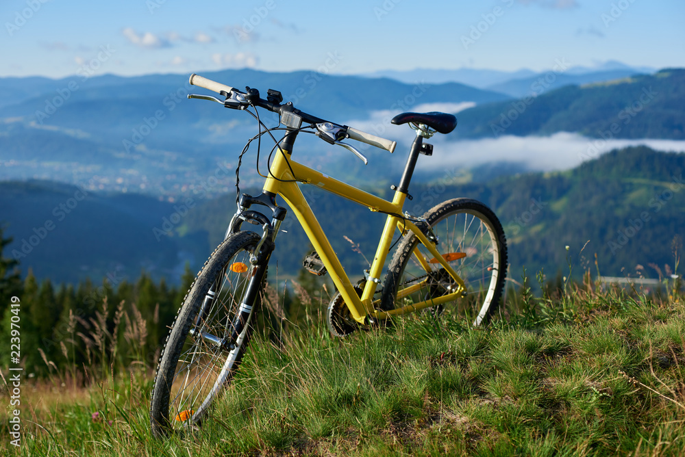 Yellow bike stands on a hill against a beautiful landscape of the powerful Carpathian mountains wrapped in smoke