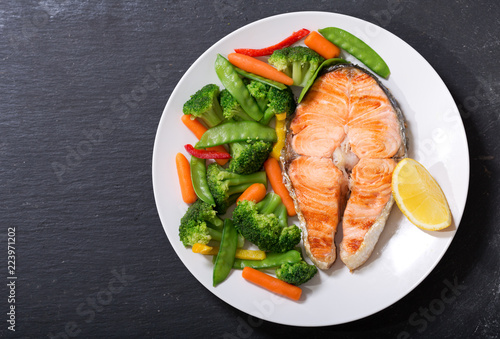 plate of grilled salmon steak with vegetables, top view