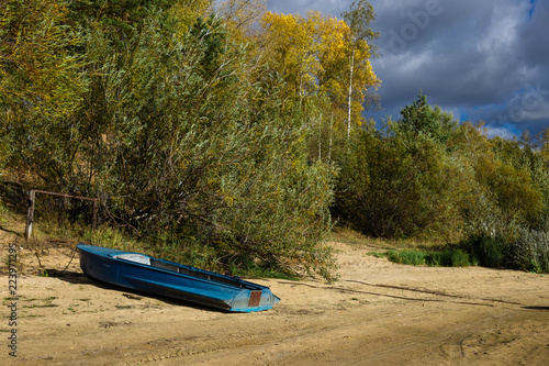 ,boat on the river Bank with thickets of trees in early autumn on a windy cloudy day